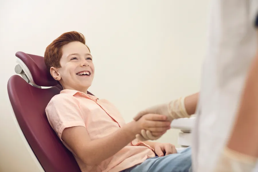 A child sitting in a medical chair, receiving a checkup or treatment from a dentist