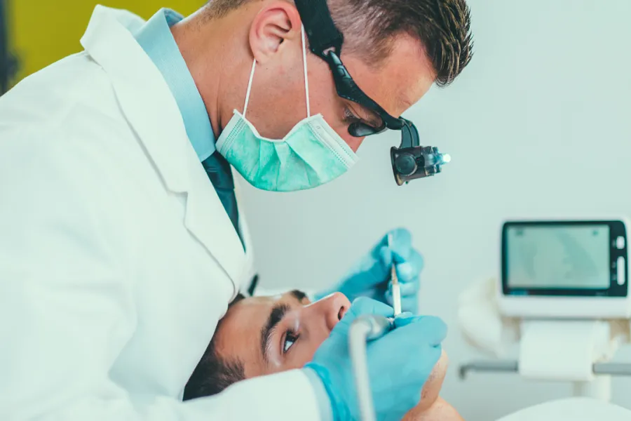 Dental professional working with tools, with a monitor in the background